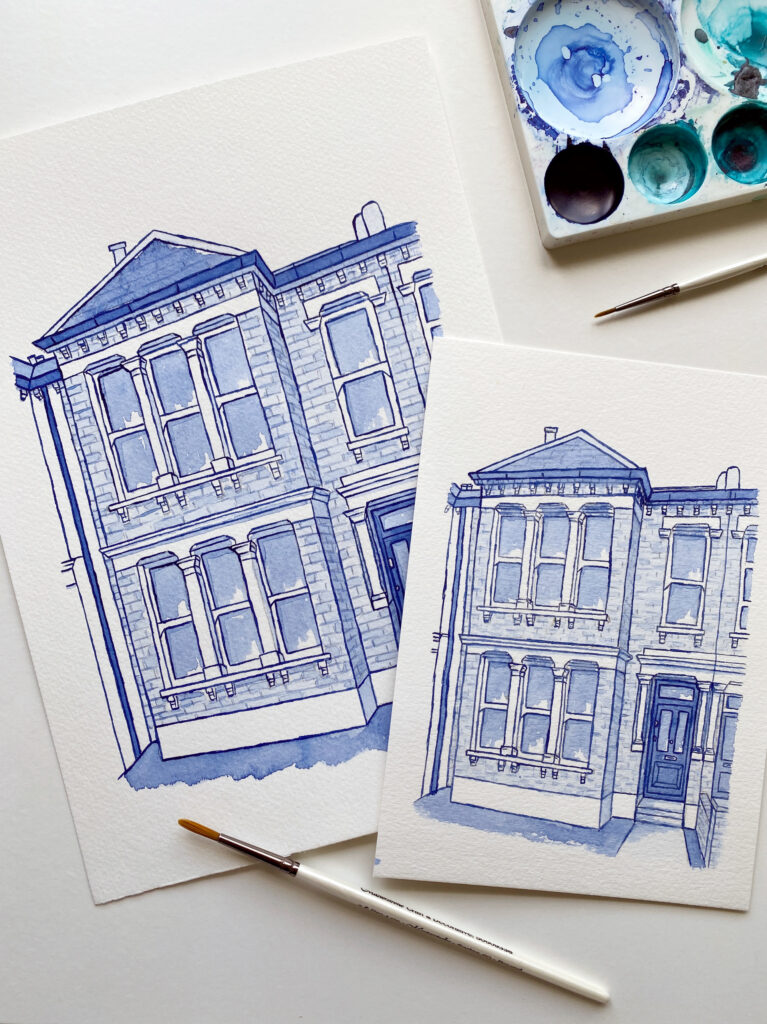 Kerri Awosile Blue Delft Style watercolour house illustrations in different sizes, laying flat on a table with paintbrushes and a paint palette